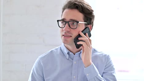 Portrait-of-Cheerful-Young-Man-Talking-on-Smartphone