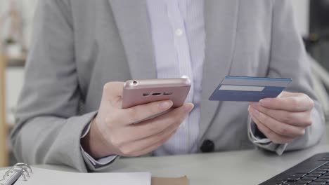 woman-hands-holding-mobile-phone-and-credit-card