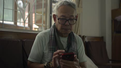 Senior-old-gray-hair-man-using-mobile-phone-for-social-online-communication-at-home.