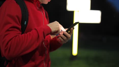 Persona-irreconocible-con-teléfono-inteligente-en-el-parque