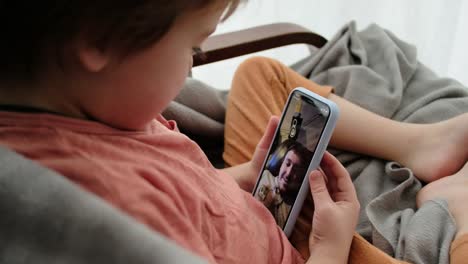 Little-boy-talks-with-father-using-videocall-on-smartphone