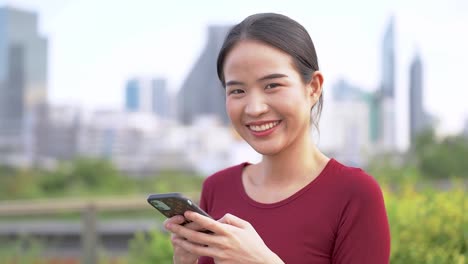 Close-up-face-of-asian-woman-using-smart-phone.-Happy-female-face-with-white-teeth-pretty-face-posing-for-close-up-portrait-outdoor.