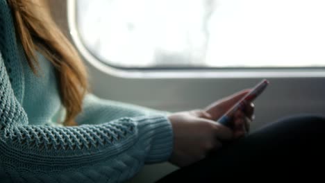 Chica-joven-viajando-en-un-tren-y-mediante-teléfono-móvil.-Hermosa-mujer-envía-un-mensaje-desde-el-teléfono-inteligente.-Chica-atractiva-charlando-con-amigos.