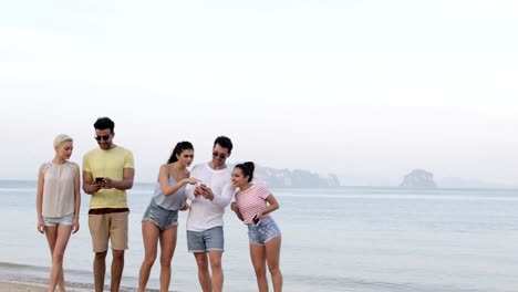 Personas-en-la-playa-usando-celular-teléfonos,-joven-sonriente-grupo-de-turistas-en-línea-de-red-inteligentes