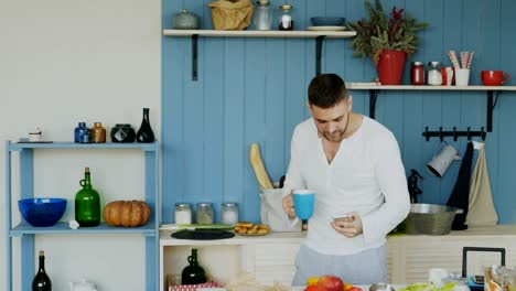 Slowmotion-von-gut-aussehenden-jungen-lustig-Mann-tanzen-und-singen-in-der-Küche-beim-Surfen-social-Media-auf-seinem-Smartphone-zu-Hause-am-Morgen