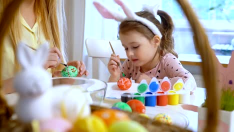 Happy-Easter!-Mother-and-her-little-daughter-wearing-funny-rabbit-ears-coloring-easter-eggs