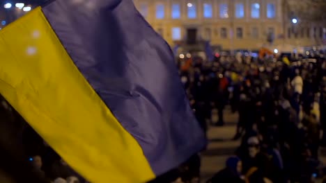 Waving-blue-and-yellow-flag-with-unfocused-crowd-background,-national-symbol