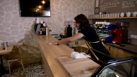 Barista-man-wiping-the-counter-when-an-female-customer-comes-in-flirts-with-him-orders-a-coffee-to-go-and-pays-with-crypto-currency-bitcoin