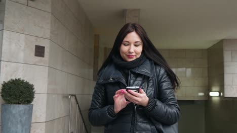 Mujer-hermosa-de-raza-mixta-con-aplicación-de-tecnología-de-teléfono-inteligente-caminando-por-las-calles-urbanas-feliz