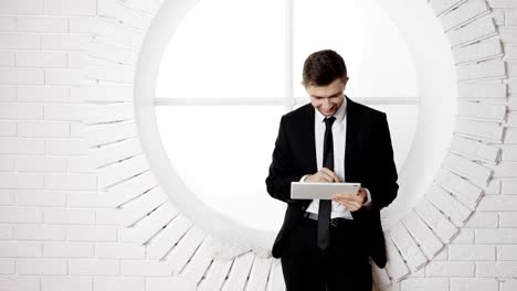 Un-hombre-joven-en-un-traje-negro-utiliza-un-PC-de-la-tableta-Digital