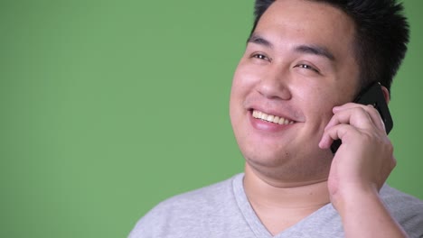 Young-handsome-overweight-Asian-man-against-green-background