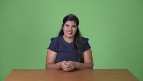 Young-overweight-beautiful-Indian-businesswoman-against-green-background