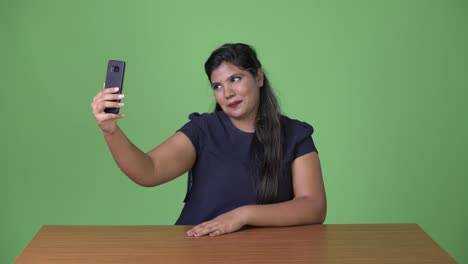 Young-overweight-beautiful-Indian-businesswoman-against-green-background