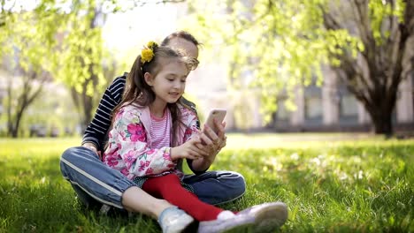 Foto-Selfie-Familie---Mutter-und-Kleinkind-Tochter-umarmt-küssen-Aufnahmen-via-Smartphone-während-des-Gehens-im-park