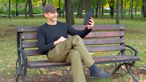 A-man-in-an-autumn-park-with-a-tablet