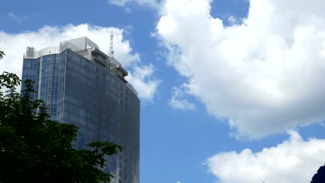 View-from-below-on-a-large-glass-business-center-against-a-background-of-moving-gray-clouds.-Reflection-in-glass