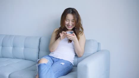 Asian-woman-using-cellphone-in-living-room