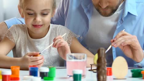 Cheerful-father-and-daughter-preparing-for-Easter,-carefully-painting-eggs