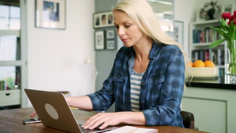 Hermosa-mujer-rubia-escribiendo-en-el-portátil-y-el-uso-de-teléfonos-inteligentes