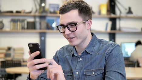 Excitada-joven-hombre-disfrutando-de-éxito-al-Smartphone-utilizando