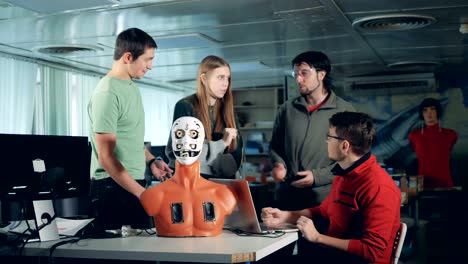 Four-engineers-working-together-with-a-humanoid,-cyborg,-robot.