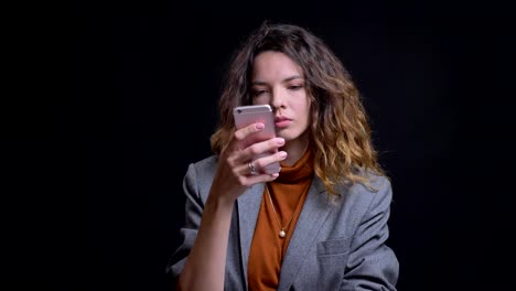 Closeup-porttait-of-modern-young-female-browsing-on-her-phone-looking-at-camera-and-laughing