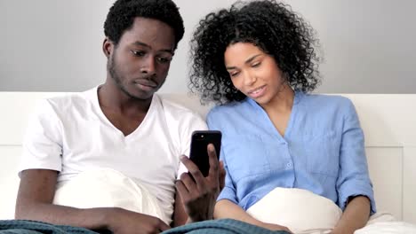 Pareja-africana-usando-smartphone-en-la-cama