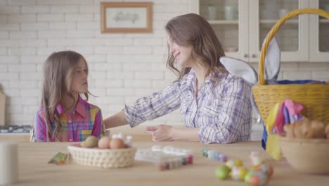 Junge-Mutter-und-ihre-vorangeklagte-Tochter-im-Gespräch-auf-der-Küche.