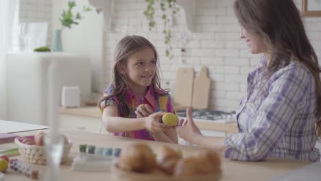 Porträt-Mutter-und-niedliche-Tochter-sitzen-am-Ostertisch.