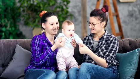 Two-smiling-adorable-young-mother-enjoying-motherhood-playing-with-little-cute-baby-at-cozy-home