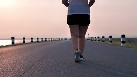 Overweight-Asian-women-jogging-in-the-street-in-the-early-morning-sunlight.-concept-of-losing-weight-with-exercise-for-health.-Slow-motion,-Bottom-view