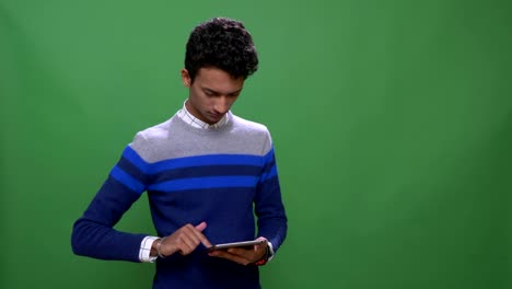 Closeup-shoot-of-young-attractive-indian-male-using-the-tablet-with-background-isolated-on-green