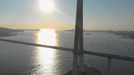 Toma-aérea-del-puente-de-cable-Russkiy-durante-la-puesta-del-sol-en-una-ciudad-de-Vladivostok,-Rusia