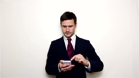 Young-handsome-businessman-pulls-out-his-smartphone-from-his-pocket-and-looks-through-the-news-feed.