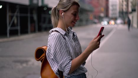 Chica-hipster-positiva-con-mochila-turística-disfrutando-de-la-comunicación-en-línea