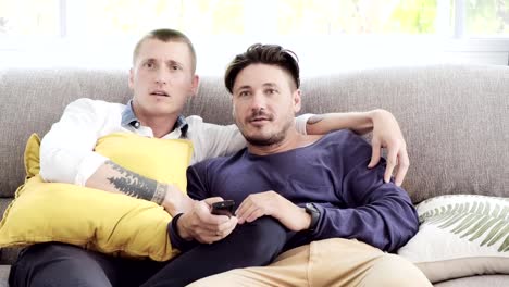 Pareja-gay-relajándose-en-el-sofá.-Disfrutar-viendo-la-televisión,-estado-de-ánimo-tenso.