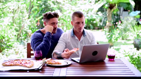 Gay-couple-having-pizza-for-lunch.-Talking-serious.