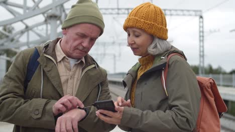 Pareja-senior-usando-gadgets-en-la-estación-de-tren