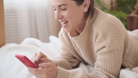 Mujer-divirtiéndose-usando-el-teléfono-móvil-en-la-cama