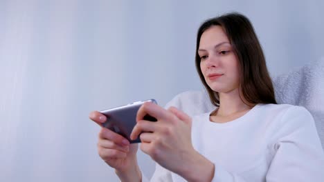 Joven-morena-mujer-está-jugando-juego-en-el-teléfono-móvil.