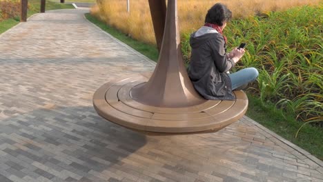 Autumn-day-Caucasian-woman-riding-a-carousel-in-circle-Holds-a-cellphone-clicks