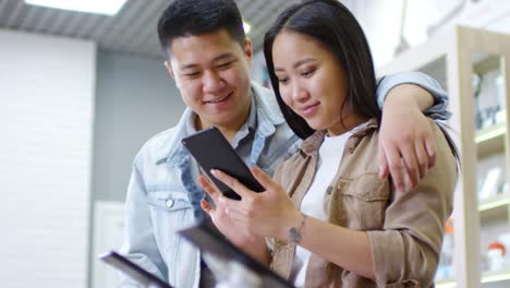 Asian-Couple-Testing-Smartphone-and-Smiling