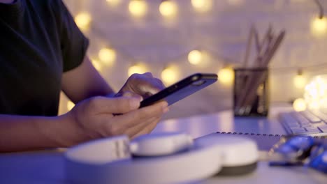 Close-up-shot-of-Female-hands-using-smart-phone-in-office-at-night