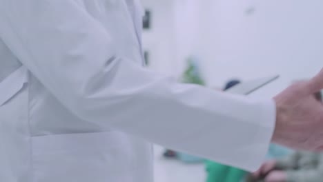 Male-doctor-with-tablet-shaking-hand-of-female-colleague-in-hospital,-team-work