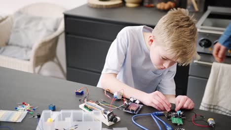 Grandson-With-Grandfather-Assembling-Electronic-Components-To-Build-Robot-Together-At-Home