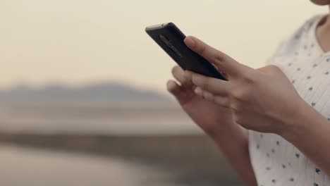 Close-up-Asian-teenage-woman-using-smartphone-in-vacation-holiday-typing-messages-sharing-social-media-enjoying-travel-summer.