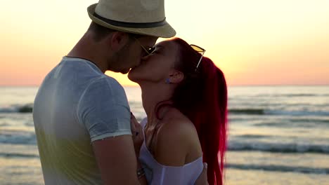 Young-beautiful-couple-kissing-at-sunrise-on-the-beach