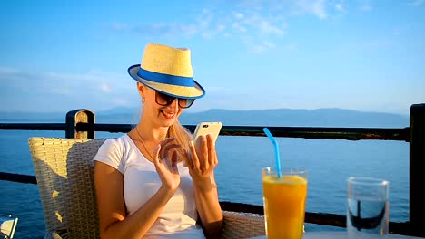 Young-happy-girl-communicates-in-social-networks-via-mobile-phone-in-a-cafe