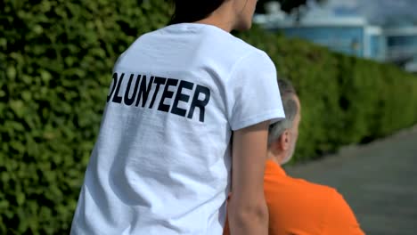 Slow-motion-of-a-helpful-volunteer-walking-with-a-wheelchaired-man