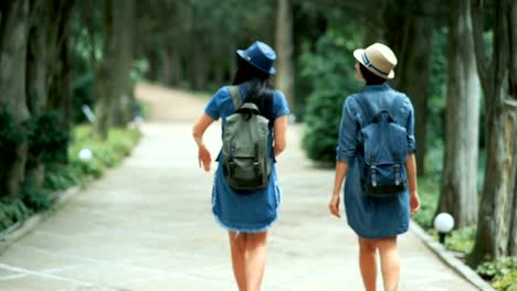 Two-tourist-women-with-backpacks-walking-in-the-park